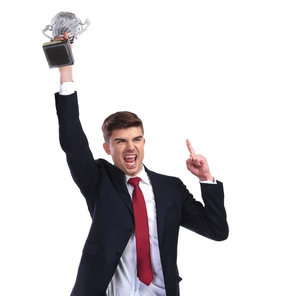 Чемпіон бізнесмен тримає трофей і вказує пальцем вгору — стокове фото