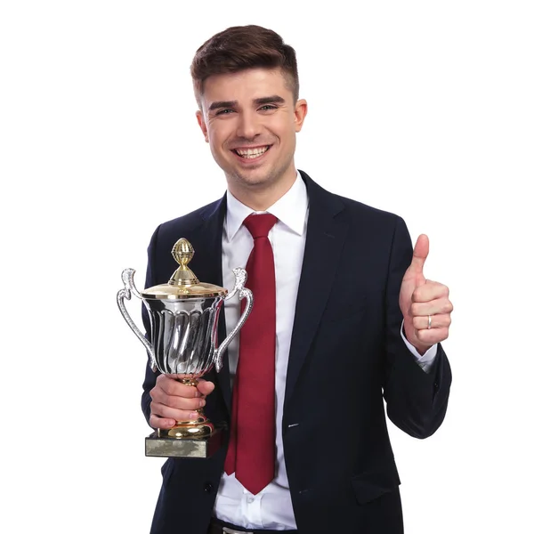 Retrato de un joven empresario sosteniendo trofeo y haciendo señal de ok — Foto de Stock