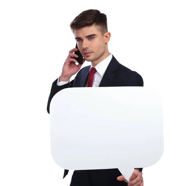 Business man holding a speech bubble while talking on the phone — стоковое фото