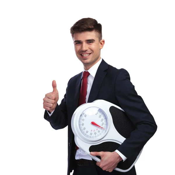 Smiling businessman holding a scale makes ok sign — Stock Photo, Image