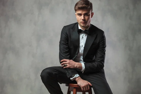 Handsome businessman sitting on chair fixes his tuxedo sleeve — Stock Photo, Image