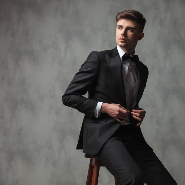 Seated businessman buttoning his suit and looking to side — Stock Photo, Image