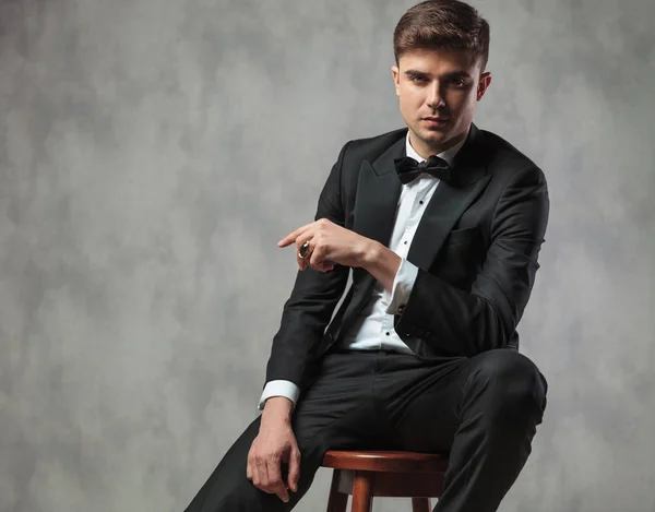 Sexy man gekleed elegant zitten en wijst naar de kant — Stockfoto