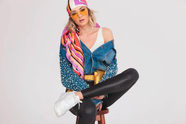 Blondynka z rock kolorowy strój siedzi ze skrzyżowanymi nogami — Zdjęcie stockowe
