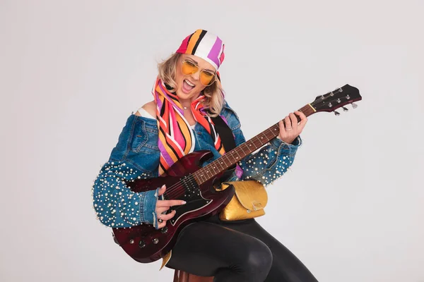 Жінка з барвистим хедкарфом грає рок-пісню на гітарі — стокове фото