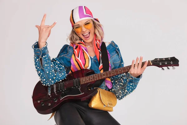Podekscytowana kobieta gra na gitarze i sprawia, że rock na znak — Zdjęcie stockowe