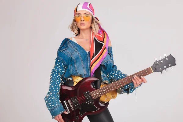 Mujer estrella de rock con miradas a un lado mientras sostiene la guitarra —  Fotos de Stock