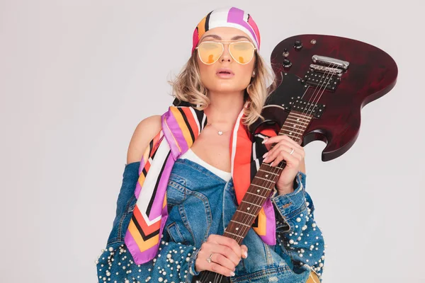 Σαγηνευτική γυναίκα με κίτρινα γυαλιά ηλίου κατέχει ηλεκτρική κιθάρα — Φωτογραφία Αρχείου