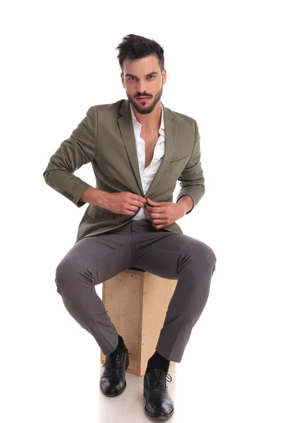 Handsome elegant man unbuttoning suit jacket while sitting — Stock Photo, Image