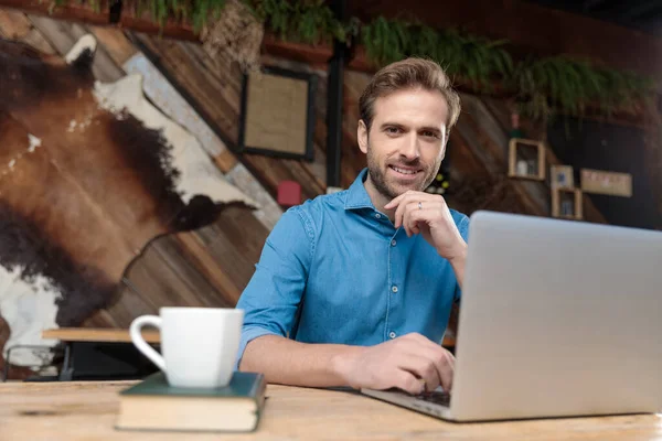 Fiducioso uomo d'affari sorridente e al lavoro sul suo portatile — Foto Stock