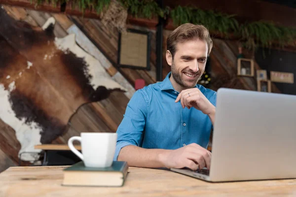 Vrolijke casual man lachen en lezen vanaf zijn laptop — Stockfoto