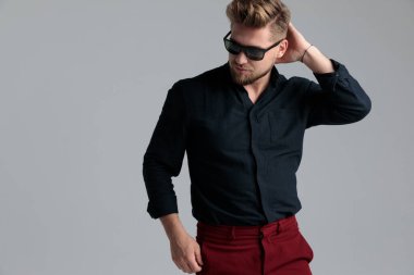 Düşünceli moda adamı başını kaşıyor ve başka tarafa bakıyor.