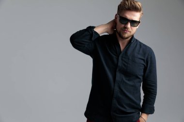 Kendine güvenen moda adamı elini boynunun arkasında tutuyor. 