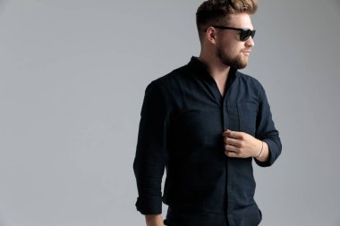 Umutlu moda adamı gömleğini düzeltiyor ve başka tarafa bakıyor. 