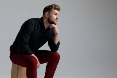 Elini çenesine koyan düşünceli moda adamı.