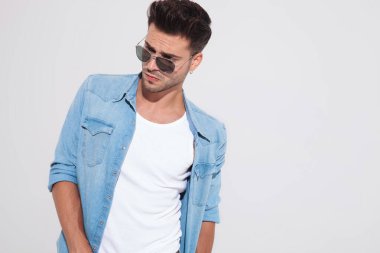 Moda adamı güneş gözlüğü takarken başka tarafa bakıyor.