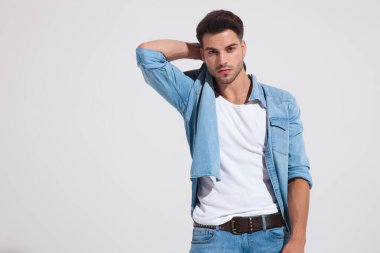 Kendine güvenen moda adamı elini boynunun arkasında tutuyor. 