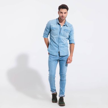 Azimli sıradan bir adam elini arka cebinde tutuyor. 