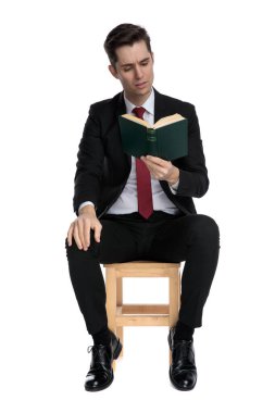 Odaklanmış işadamı otururken kitap okuyor