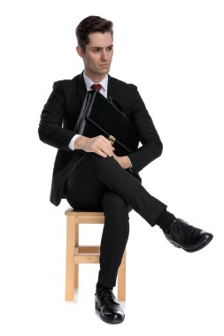 Canı sıkkın işadamı çantasını tutuyor ve başka tarafa bakıyor. 