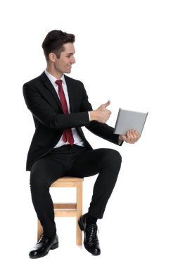 Yakışıklı iş adamı tabletini sunuyor ve başparmağını sallıyor.