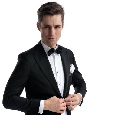 Genç moda adamı beyaz arka planda ceket düzenliyor.