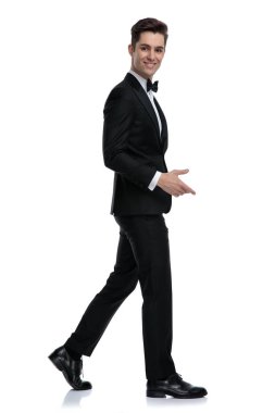 Gülümseyen ve yürüyen zarif genç adamın yan görünüşü