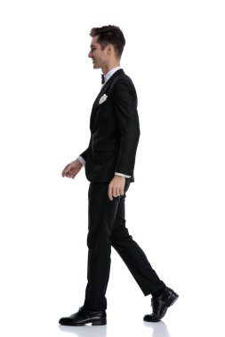 Gülümseyen ve yürüyen zarif genç adamın yan görünüşü