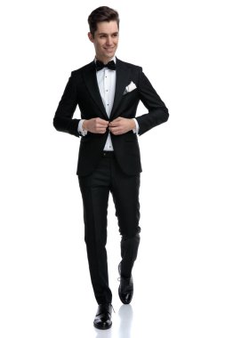 Genç ve zarif damat yürüyor ve montunu düzenliyor.