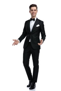 Gülümseyen genç ve zarif damat yürüyor ve davet ediyor