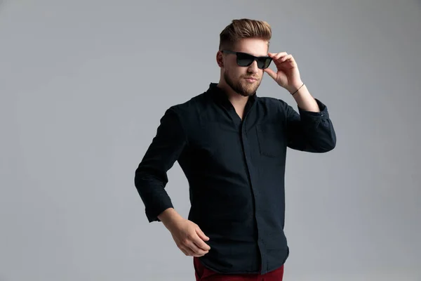 Sebevědomý módní muž si sundává sluneční brýle a dívá se jinam — Stock fotografie