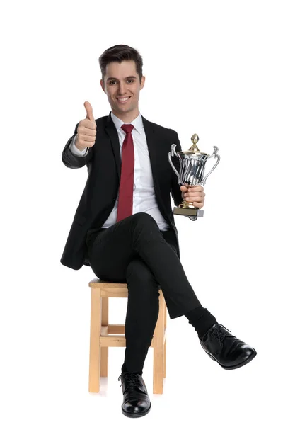 Aantrekkelijke zakenman die zijn trofee vasthoudt en een duim opsteekt — Stockfoto