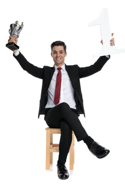 Biznesmen świętuje ze swoim trofeum i trzyma numer jeden — Zdjęcie stockowe
