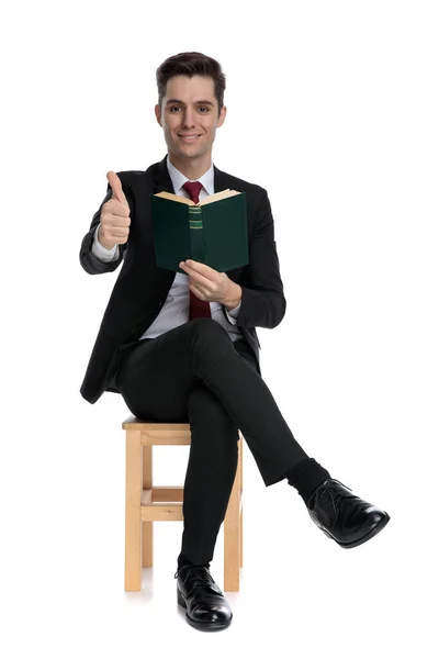 Positieve zakenman die een boek vasthoudt en een duim opsteekt — Stockfoto