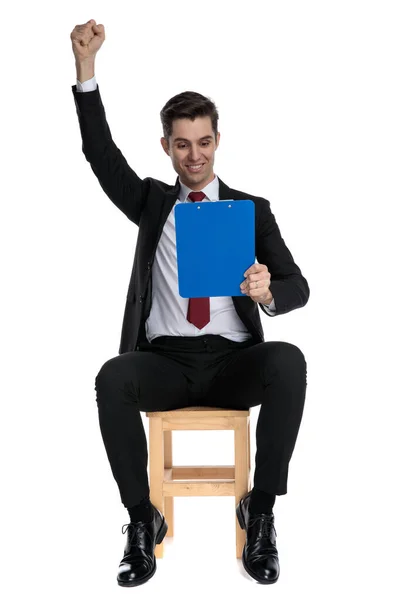 Empresário inteligente celebrando e segurando uma área de transferência azul — Fotografia de Stock