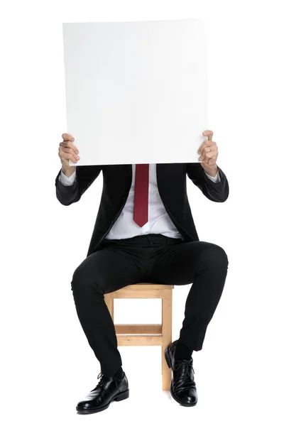Elegante zakenman bedekt zijn gezicht met een leeg reclamebord — Stockfoto