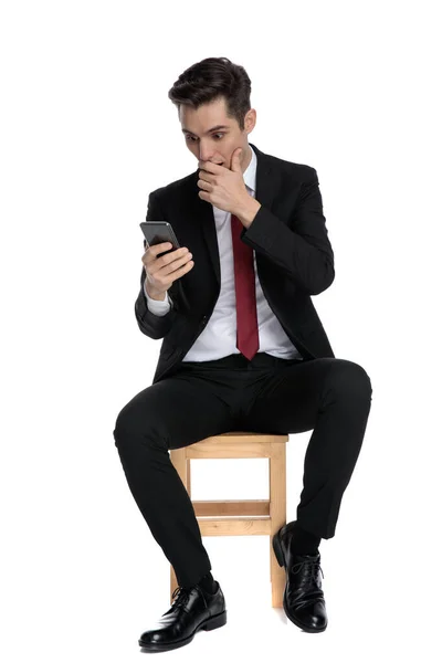 Shicked young businessman covering his mouth and holding his pho — Stock Photo, Image