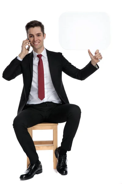 Веселый бизнесмен разговаривает по телефону, держа в руках речевой пузырь — стоковое фото