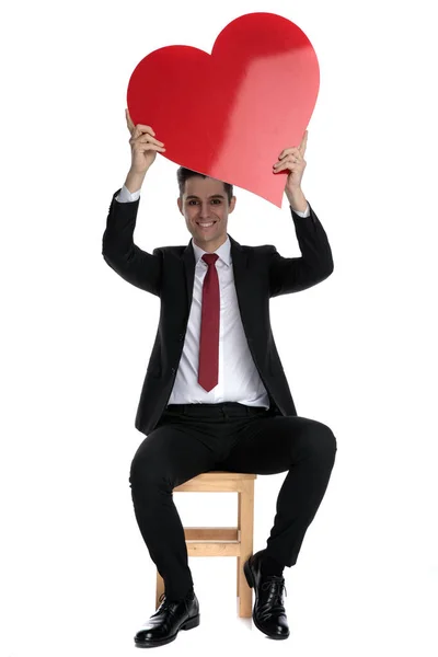 Hombre de negocios alegre sosteniendo una forma de corazón por encima de su cabeza —  Fotos de Stock