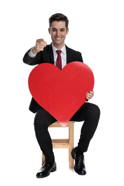 Atrakcyjny biznesmen wskazujący do przodu i utrzymujący kształt serca — Zdjęcie stockowe
