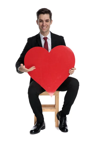 Stilig ung affärsman presenterar en hjärtform — Stockfoto