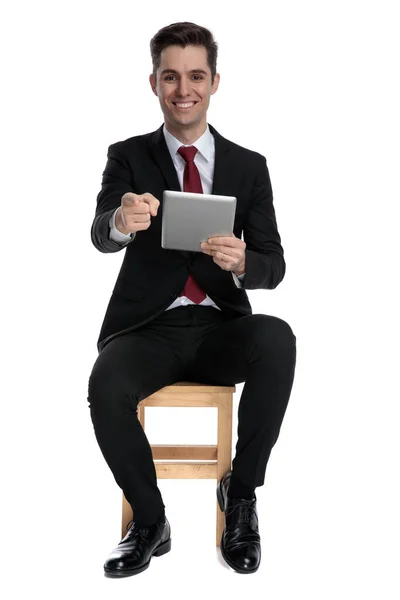 Gelukkige zakenman wijst naar voren en houdt zijn tablet vast — Stockfoto