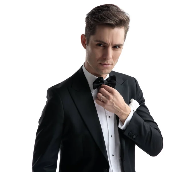 Young elegant groom in tuxedo fixing bowtie — Stock Photo, Image