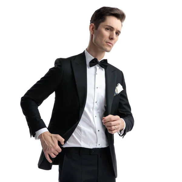 Joven elegante hombre mirando a un lado y tirando de abrigo — Foto de Stock