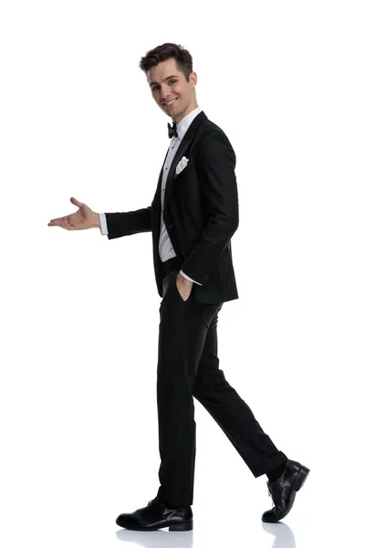 Vista lateral del joven hombre elegante caminando y presentando a un lado —  Fotos de Stock