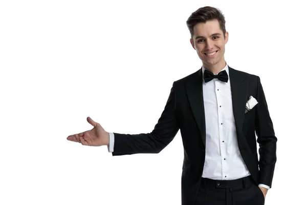 Modelo jovem feliz em smoking sorrindo e apresentando ao lado — Fotografia de Stock