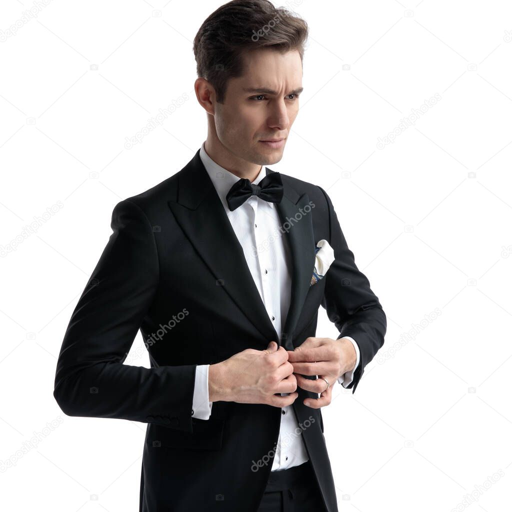 serious young man looking to side and arranging coat