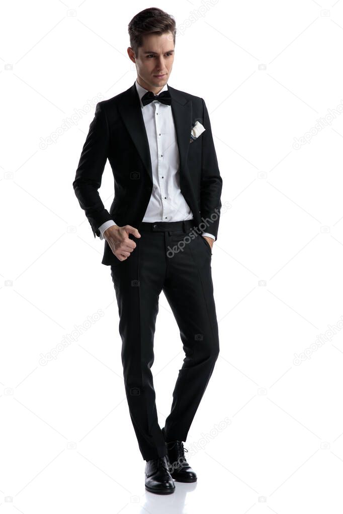 young elegant groom wearing tuxedo and looking to side