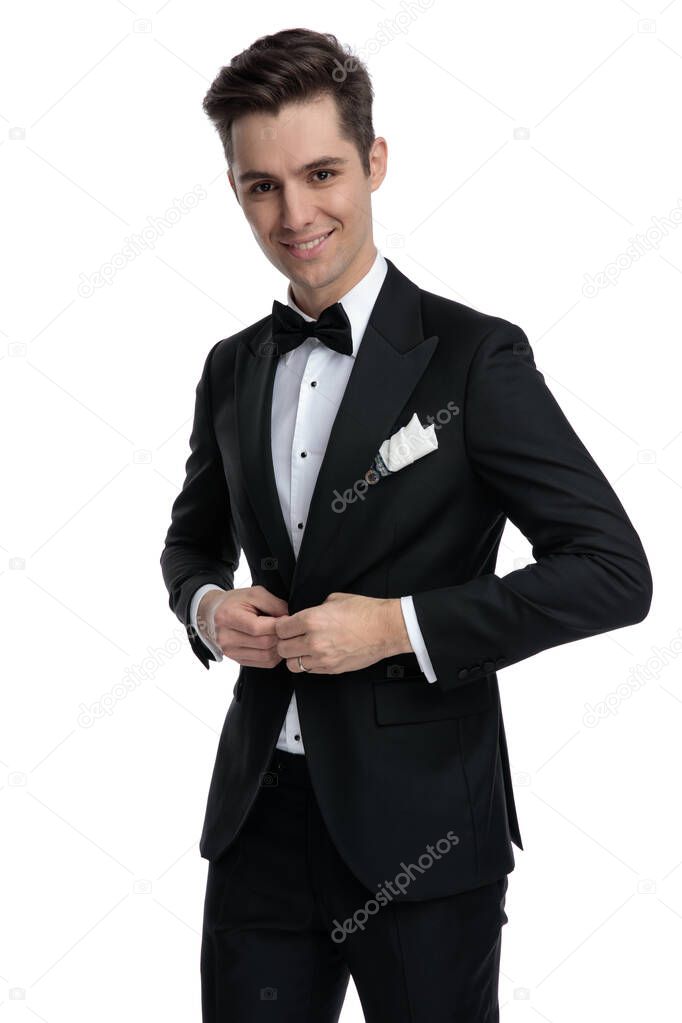 young modern guy in tuxedo smiling and arranging coat