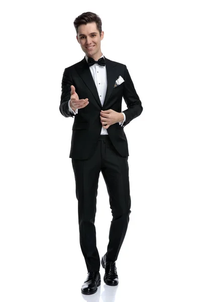 Elegantní mladý muž ve smokingu aranžování kabát a držení za ruku — Stock fotografie